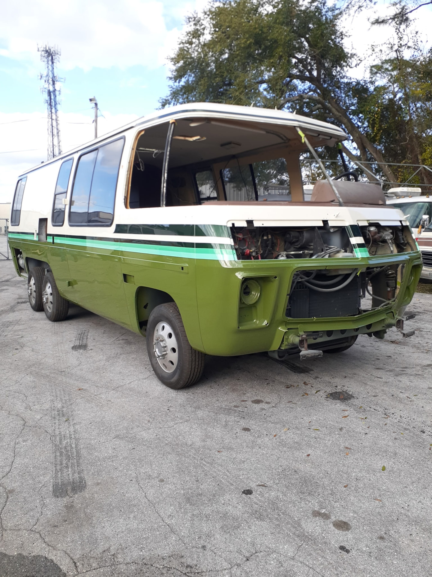 Green and white painted vintage bus in progress outdoors